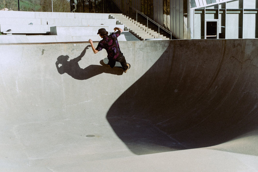 Photo of man skateboarding around a skatepark bowl. He is wearing Blinky Bills Shirt No. 1, a black over-sized, short-sleeved shirt with a print of pink and purple tattoo-designed tigers.