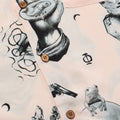 Close up photo of of Blinky Bills Shirt No. 2 coconut shell buttons. Very light pink short-sleeved shirt with print of different tattoo designs in greyscale.