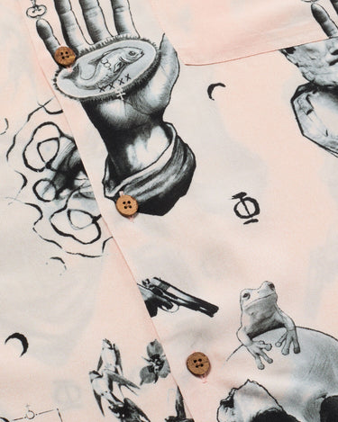 Close up photo of of Blinky Bills Shirt No. 2 coconut shell buttons. Very light pink short-sleeved shirt with print of different tattoo designs in greyscale.